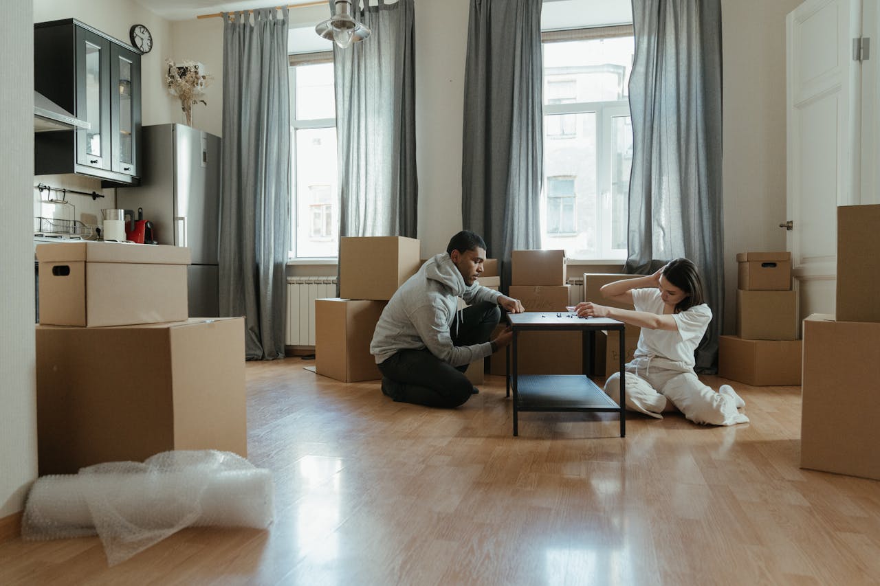 services-01 Young couple assembling furniture in their new apartment, surrounded by cardboard boxes.