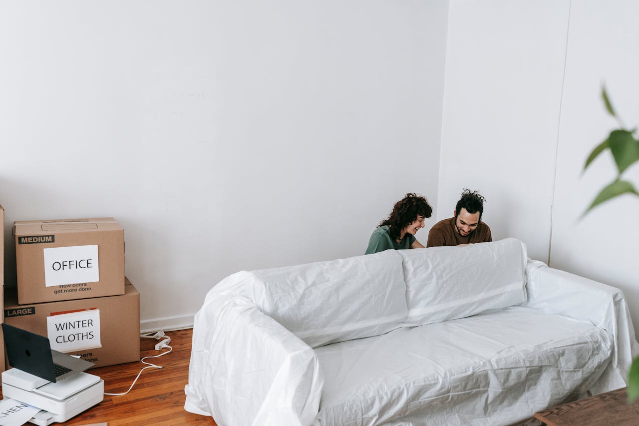 hero-img-01 A couple enjoys moving into a new home, surrounded by boxes and minimalist decor.